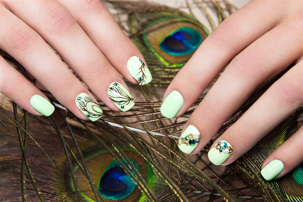 Art design manicure with peacock feather on female hands. Close up