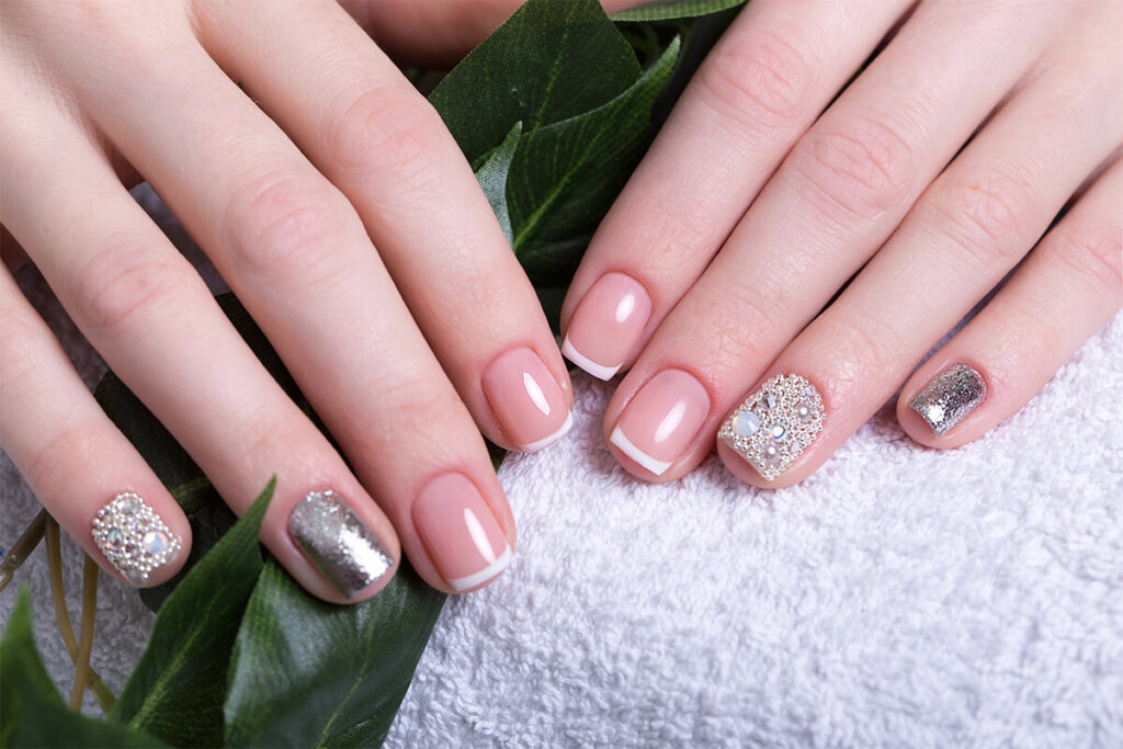 Beautiful classic French manicure with rhinestones on female hand