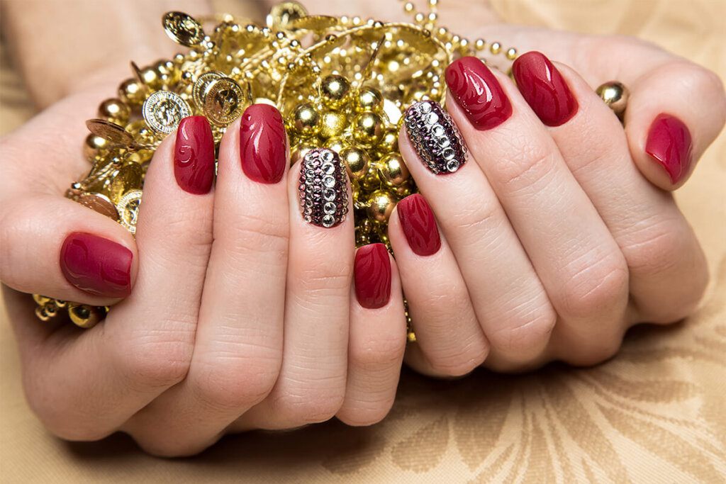 Beautiful red manicure with crystals on female hand. Close up