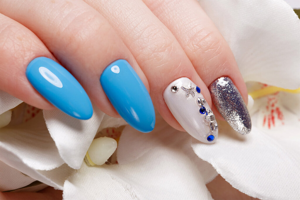 Beautiful summer blue manicure on female hand with flowers . Close up