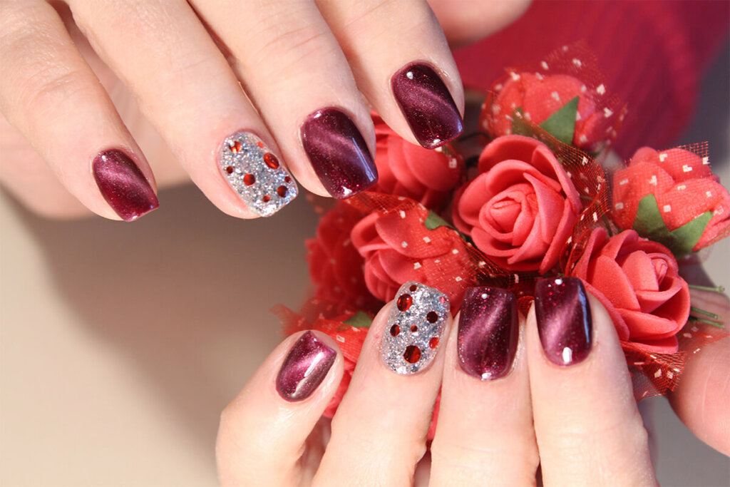 a close up of nails art polish in burgundy and silver color