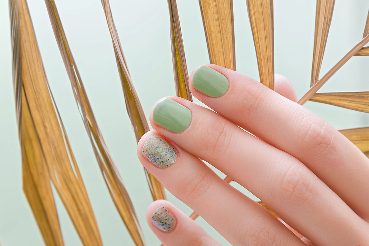 Female hand with green nail design on green background