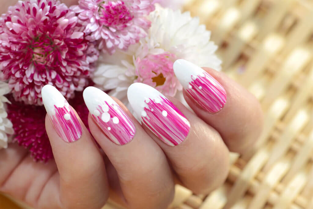 a hand with painted nails and flowers in white and pink color